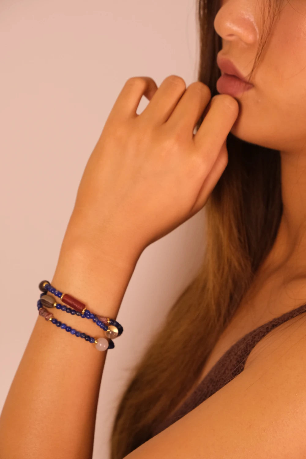Woman wearing a Luck & Healing – Tibetan Energy Mala Bracelet with beads on a plain background, Lapis Lazuli & Amber