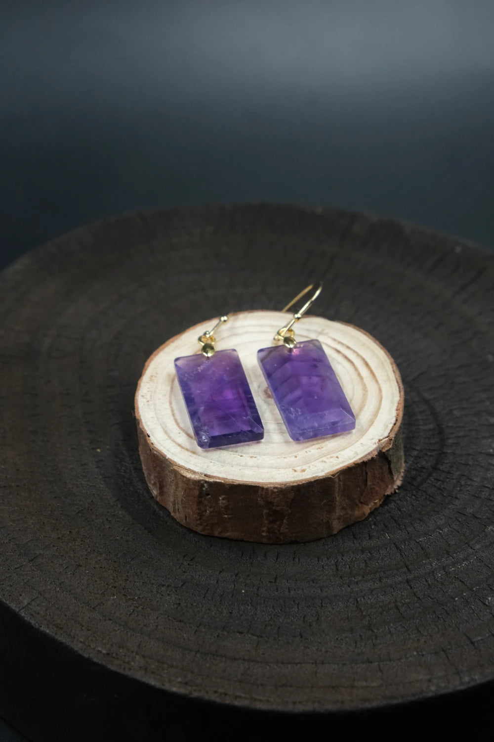 Focus & Balance – Tibetan Amethyst Earrings on a wooden stand with a dark background