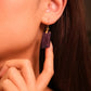 Close-up of a woman wearing Focus & Balance – Tibetan Amethyst Earrings with a blurred background