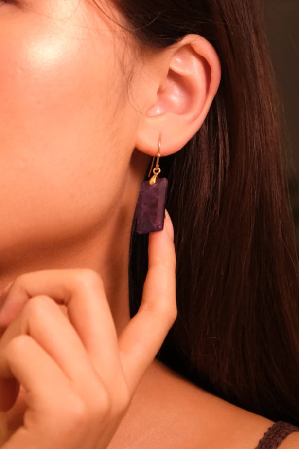 Close-up of a woman wearing Focus & Balance – Tibetan Amethyst Earrings with a blurred background
