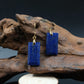 Blue rectangular earrings on a wooden stand with a dark background, Tibetan Feng Shui Crystal Earrings – Lapis Lazuli for Protection, Purification & Well-Being