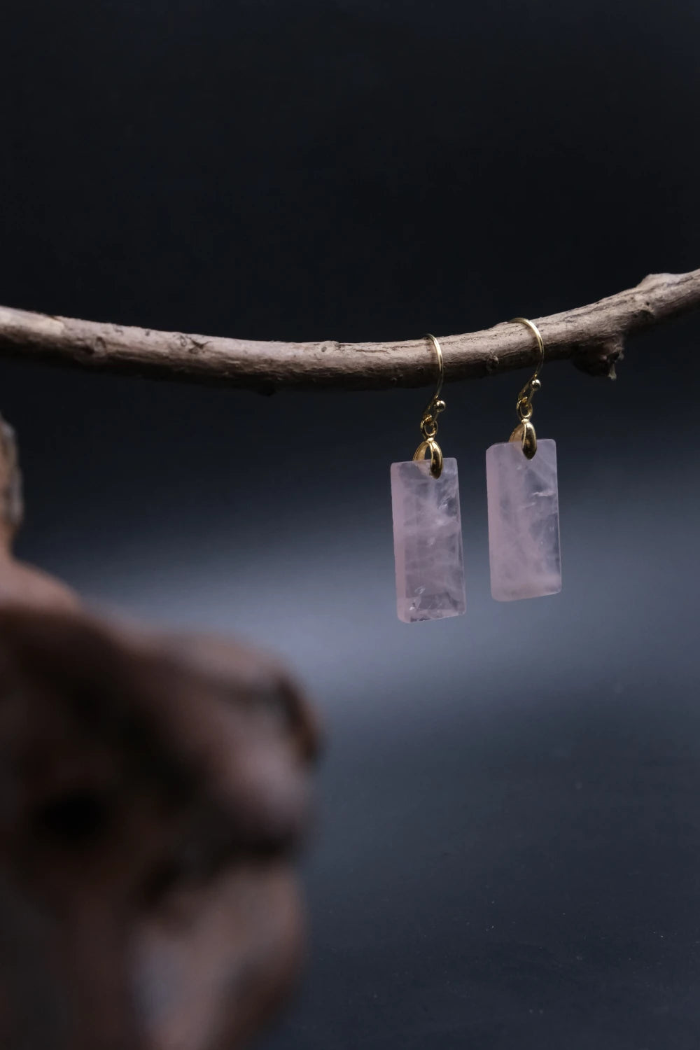 Handcrafted Tibetan Feng Shui Rose Quartz Crystal Earrings with healing energy for romance, social luck, and heart chakra balance, displayed on a branch