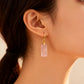 Close-up of a woman wearing a gold earring with a pink gemstone.