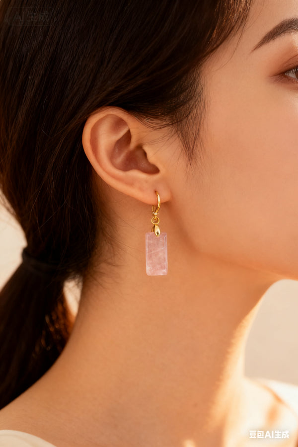 Close-up of a woman wearing a gold earring with a pink gemstone.