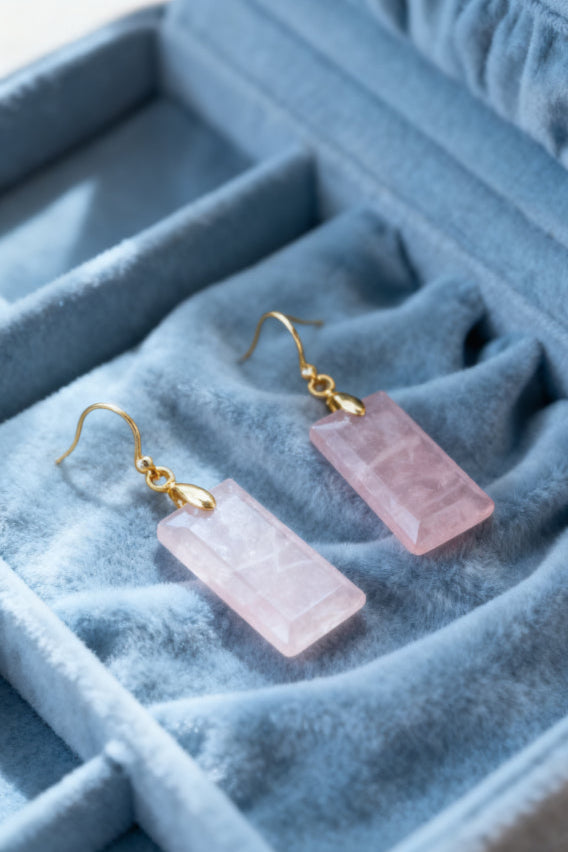 Pink crystal earrings with gold hooks on a blue velvet jewelry box