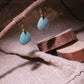 Confidence & Renewal – Tibetan Amazonite Earrings hanging from a branch on a textured fabric background