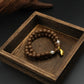 Close - up of Tibetan Five Elements Aromatherapy Bracelet: Natural brown aromatherapy beads paired with lustrous pearls and a golden foot charm, designed for protection, balance, and inner peace.