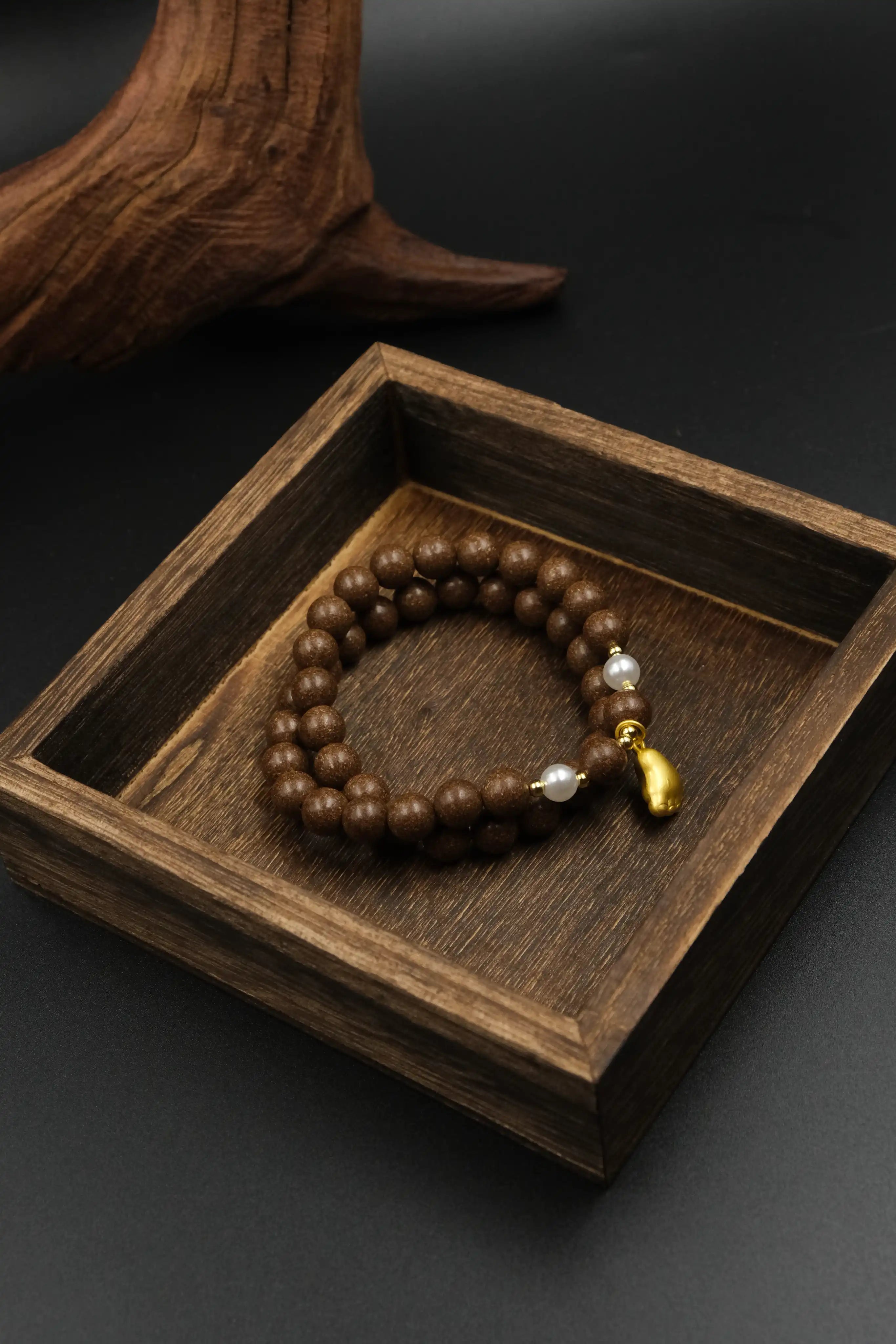 Close - up of Tibetan Five Elements Aromatherapy Bracelet: Natural brown aromatherapy beads paired with lustrous pearls and a golden foot charm, designed for protection, balance, and inner peace.
