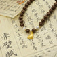 Tibetan Pearl Five Elements Bracelet  with a gold charm on top of Chinese text