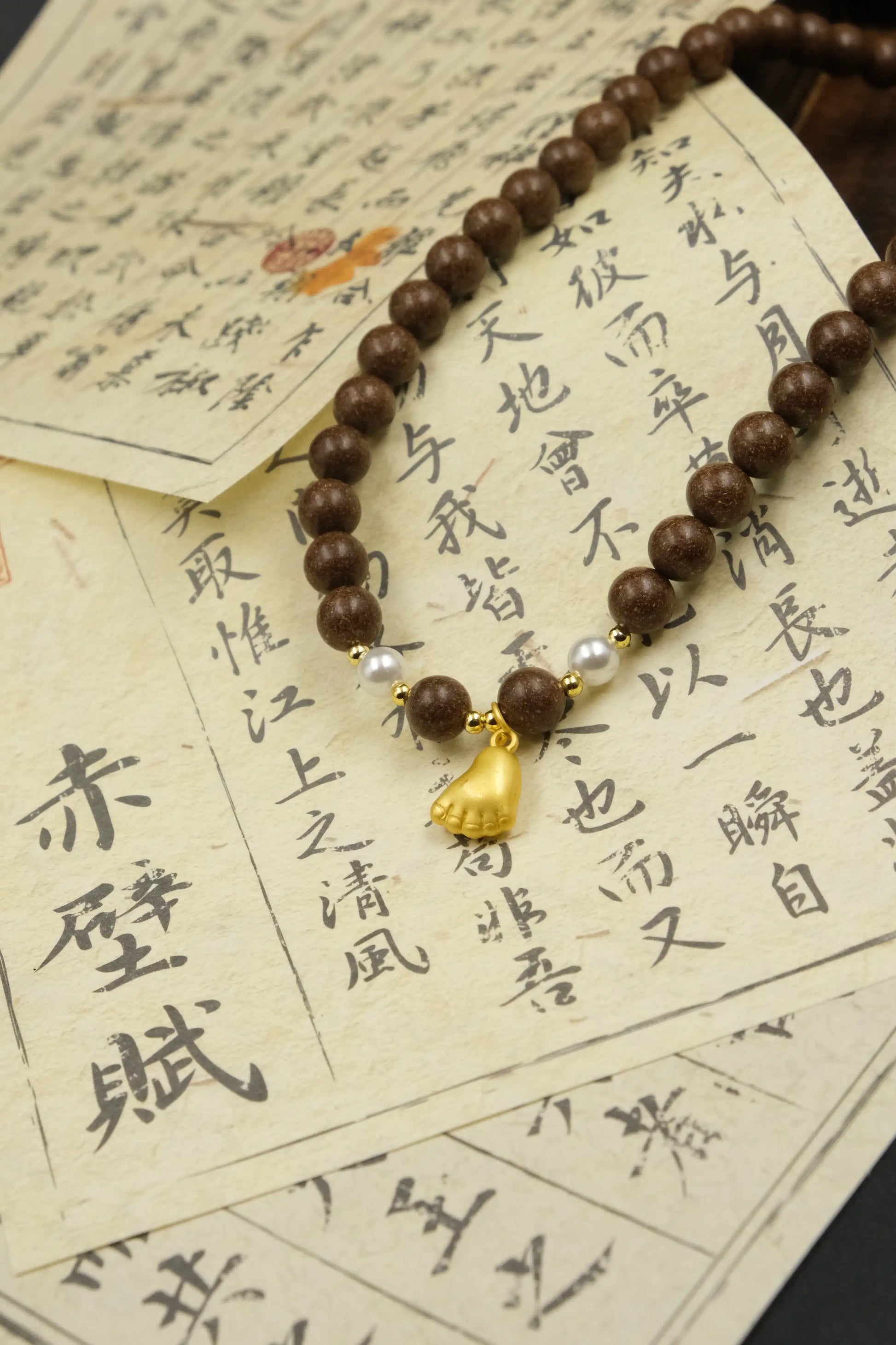 Tibetan Pearl Five Elements Bracelet  with a gold charm on top of Chinese text