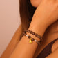 Close-up of a person wearing a Natural Aromatherapy Beads with Pearls & Golden Foot Charm for Protection, Balance & Inner Peace, with a bell charm on a neutral background