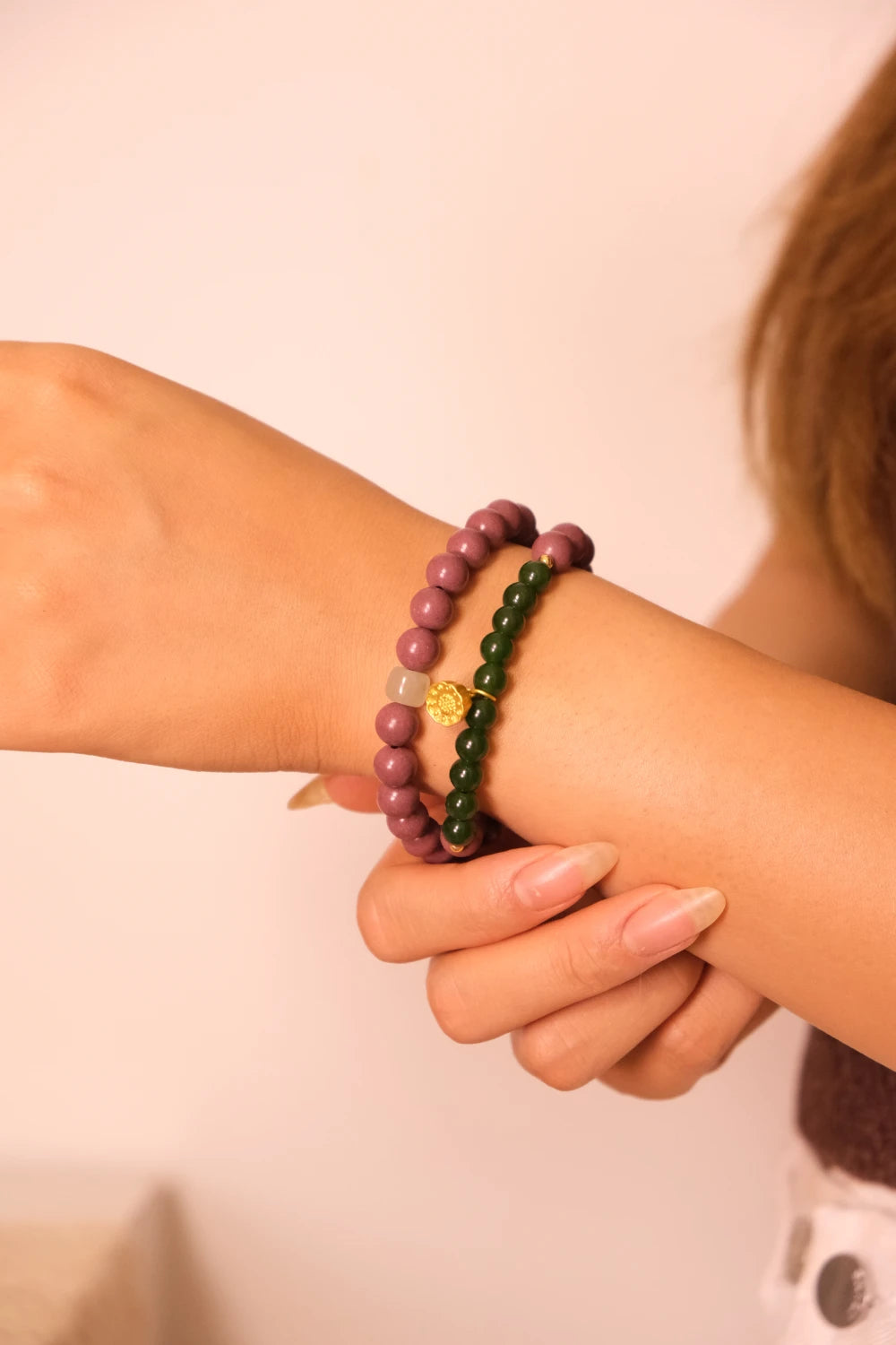 Close-up of a wrist wearing two-cycle Aromatherapy beaded bracelets on a plain background