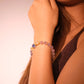 Close-up of a woman's arm wearing a Healing & Abundance – Tibetan Five Elements Flow Bracelet against a neutral background