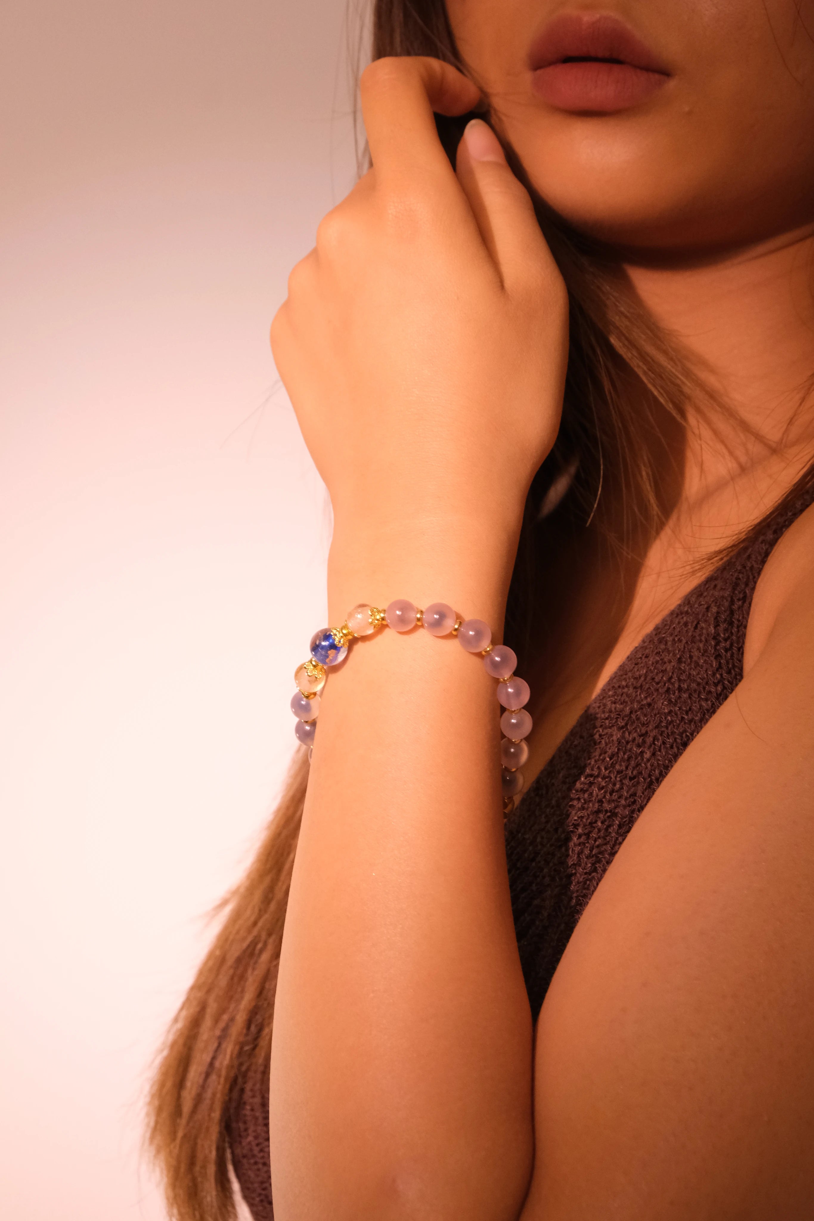 Close-up of a woman's arm wearing a Healing & Abundance – Tibetan Five Elements Flow Bracelet against a neutral background