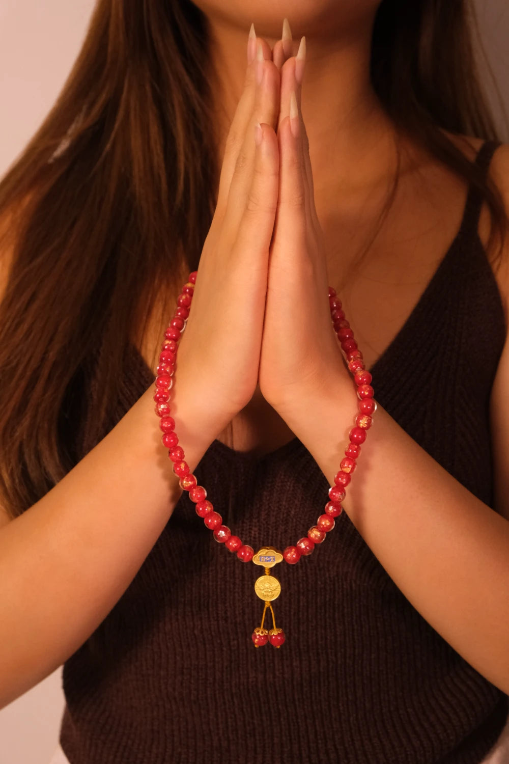 Person wearing a Vitality & Prosperity  Tibetan Five Elements Flow Bracelet with hands in prayer position against a neutral background
