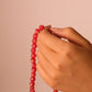 Hand holding a Vitality & Prosperity Tibetan Five Elements Flow Braceletagainst a beige background