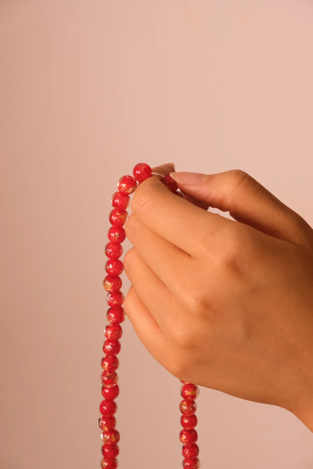 Hand holding a Vitality & Prosperity Tibetan Five Elements Flow Braceletagainst a beige background