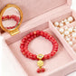 Red beaded bracelet with a gold charm in an open jewelry box with a mirror.