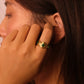 Close-up of a person wearing a gTibetan Five Elements Ring on Malachite gemstone, touching their ear.