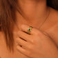 Close-up of a hand wearing a gold ring with malachite stone on a blurred background