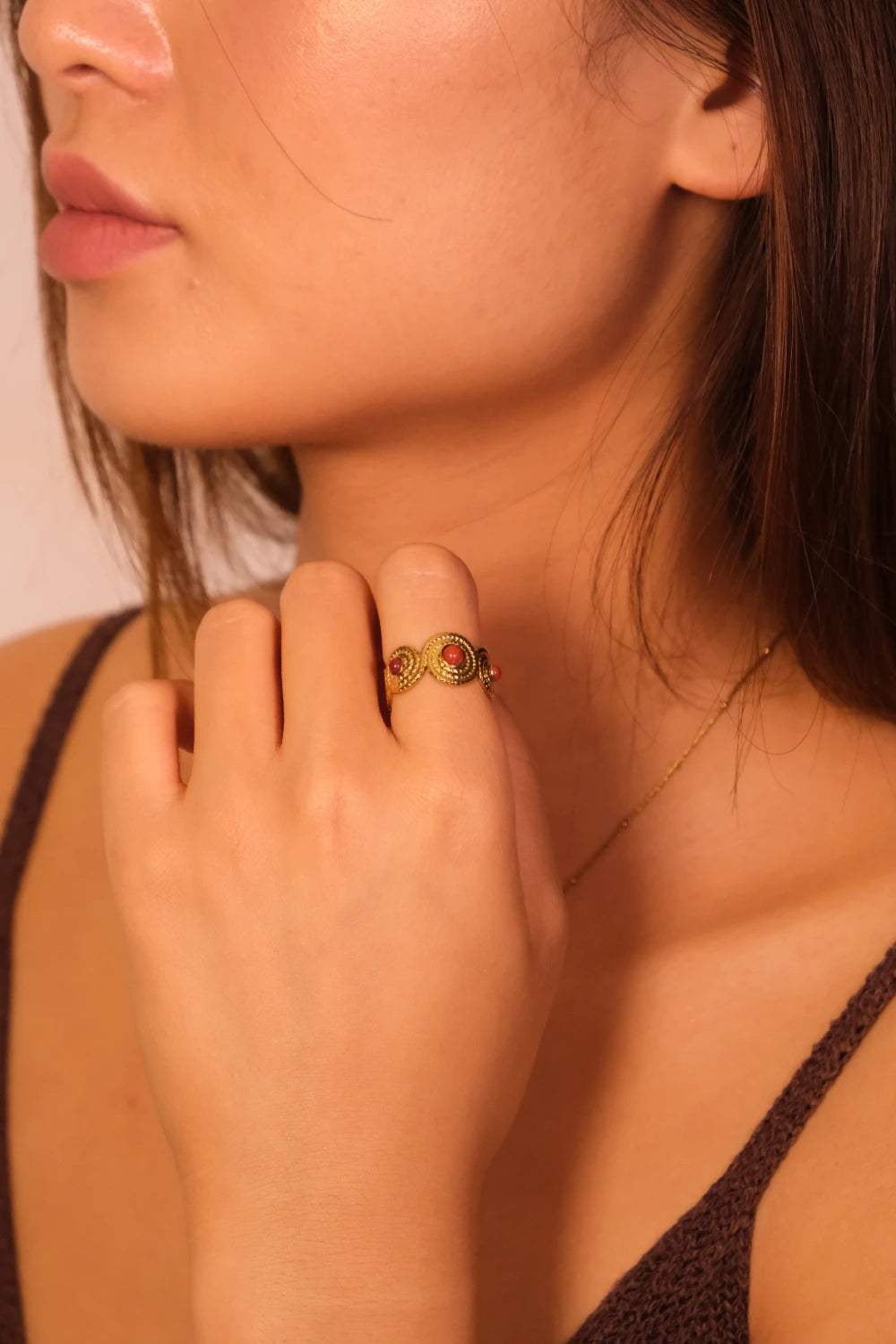Close-up of a woman wearing a Tibetan Red Agate Five Elements Ring on a neutral background