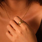 Close-up of a hand wearing a gold ring with a Red Agate gemstone against a blurred background
