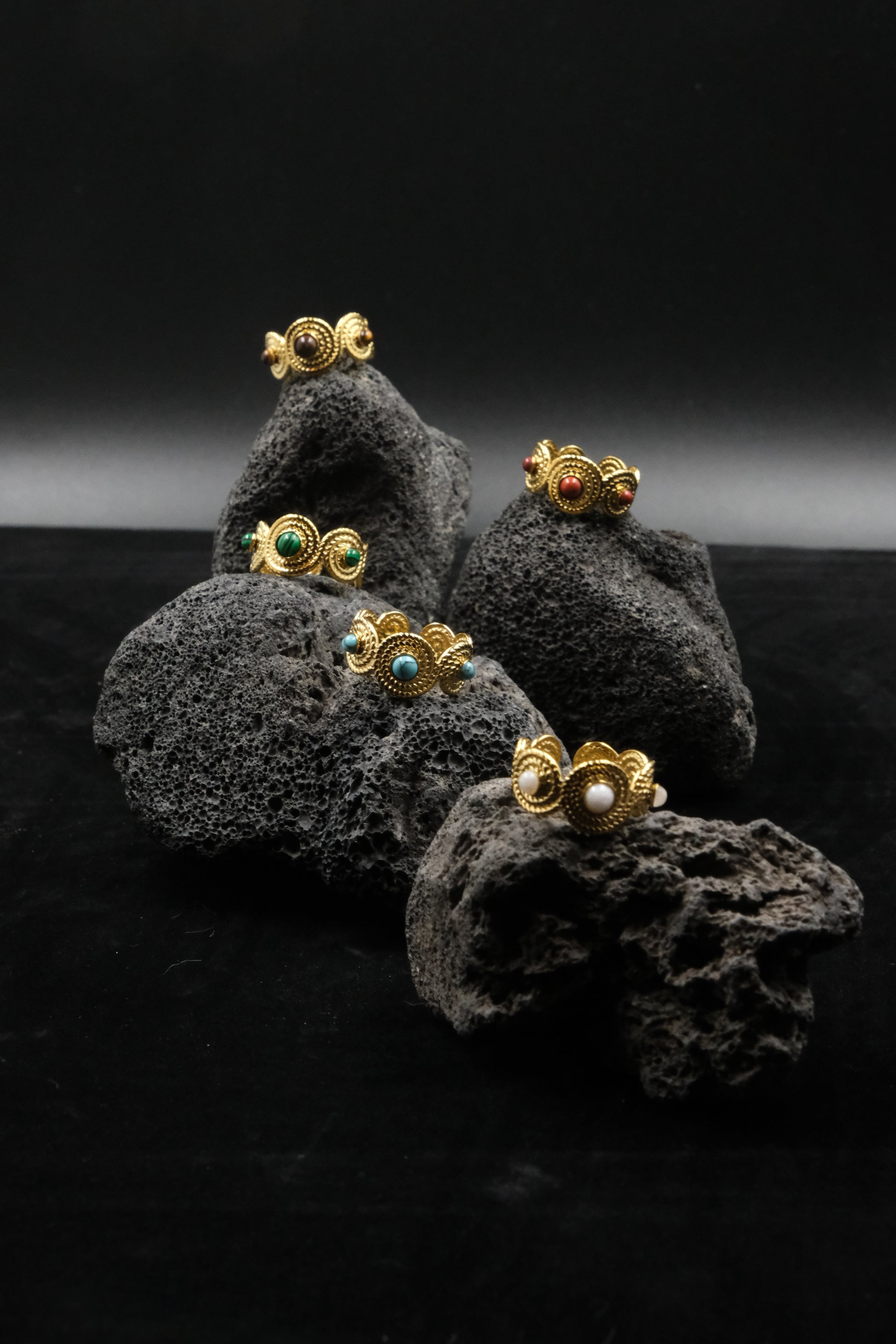 Gold earrings with gemstones on a dark textured surface. Tibetan Five Elements Ring – Tiger’s Eye for Success & Abundance
