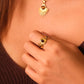 Close-up of a person wearing a gold Tibetan Five Elements Ring – Tiger’s Eye for Success & Abundance ring  and necklace with a sun design.