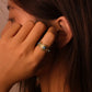 Close-up of a person wearing a gold earring with a blue gemstone.Tibetan Five Elements Ring