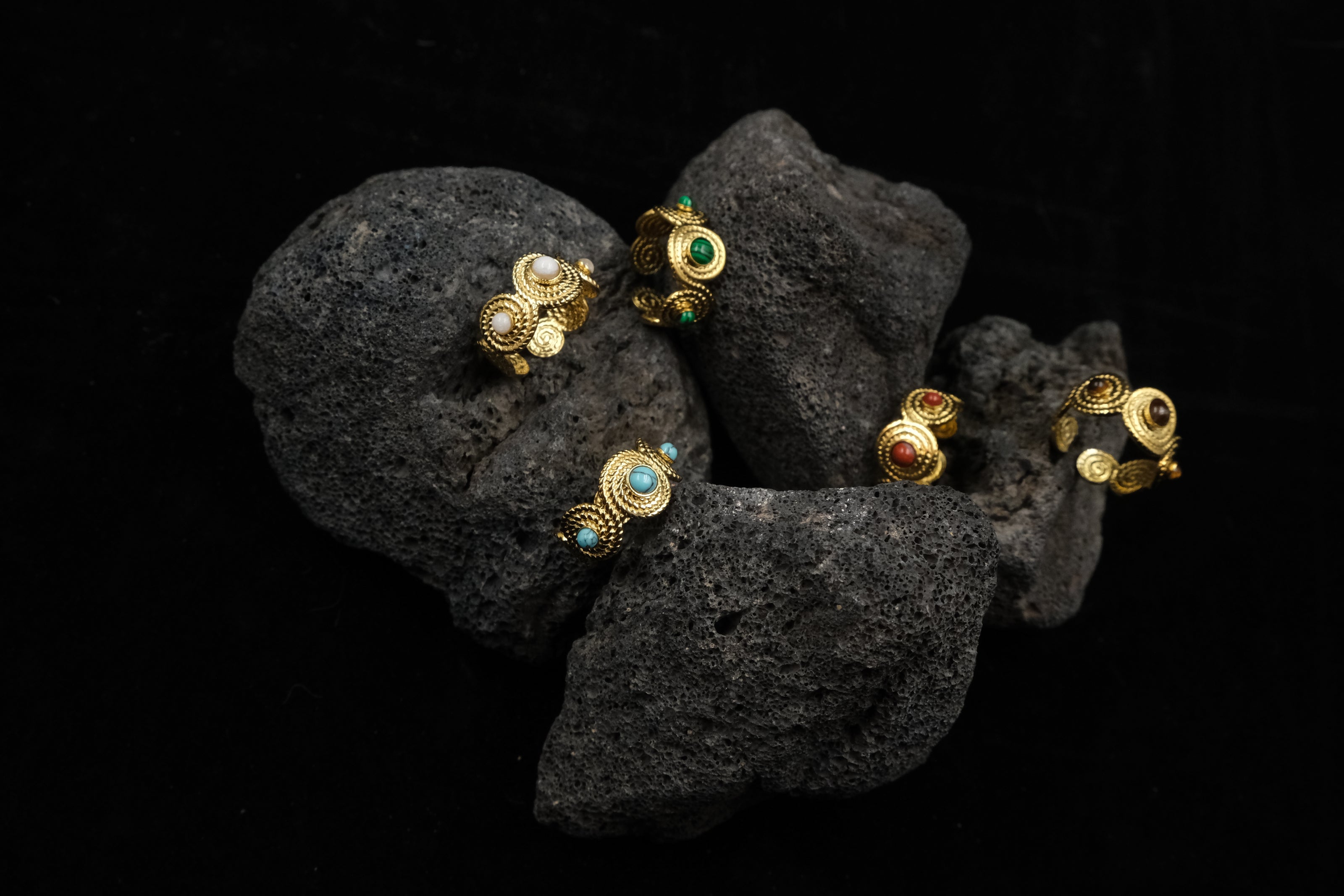Tibetan Five Elements Rings with gemstones on a black stone surface