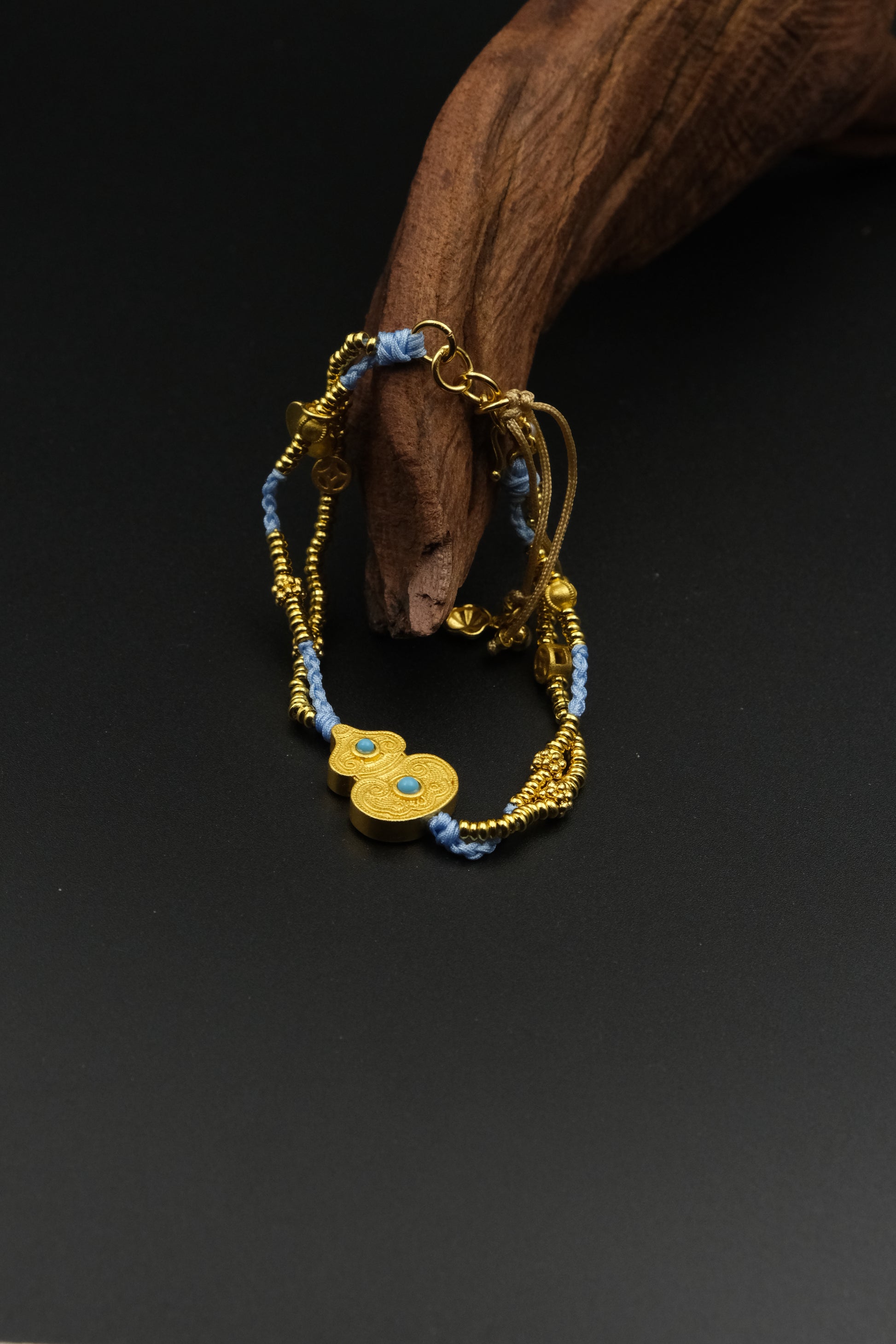 Luxury handmade gold and blue beaded bracelet with woven cord, double round gold charm, and turquoise accents.