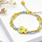 Gold and blue bracelet on a white surface with dried flowers