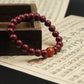 Red beaded bracelet,Spiritual_Protection_Inner_Wisdom_Emotional_Balance, with a large amber bead on an old text document