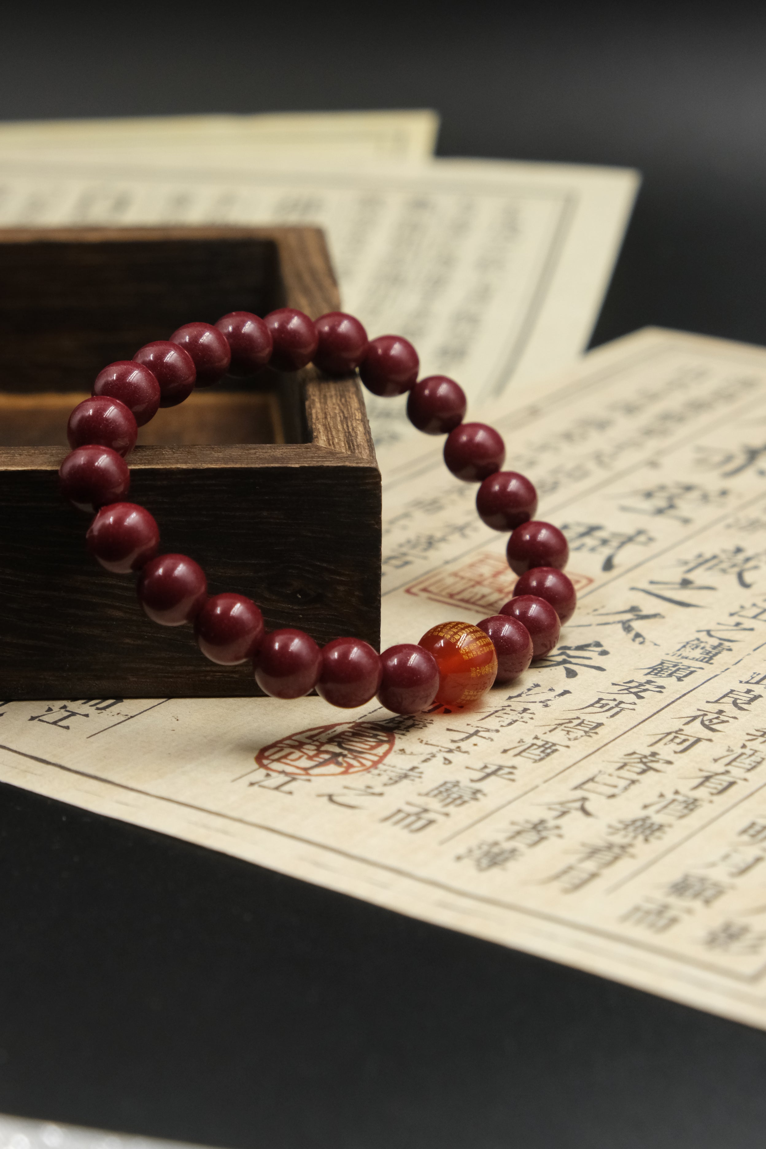 Red beaded bracelet,Spiritual_Protection_Inner_Wisdom_Emotional_Balance, with a large amber bead on an old text document