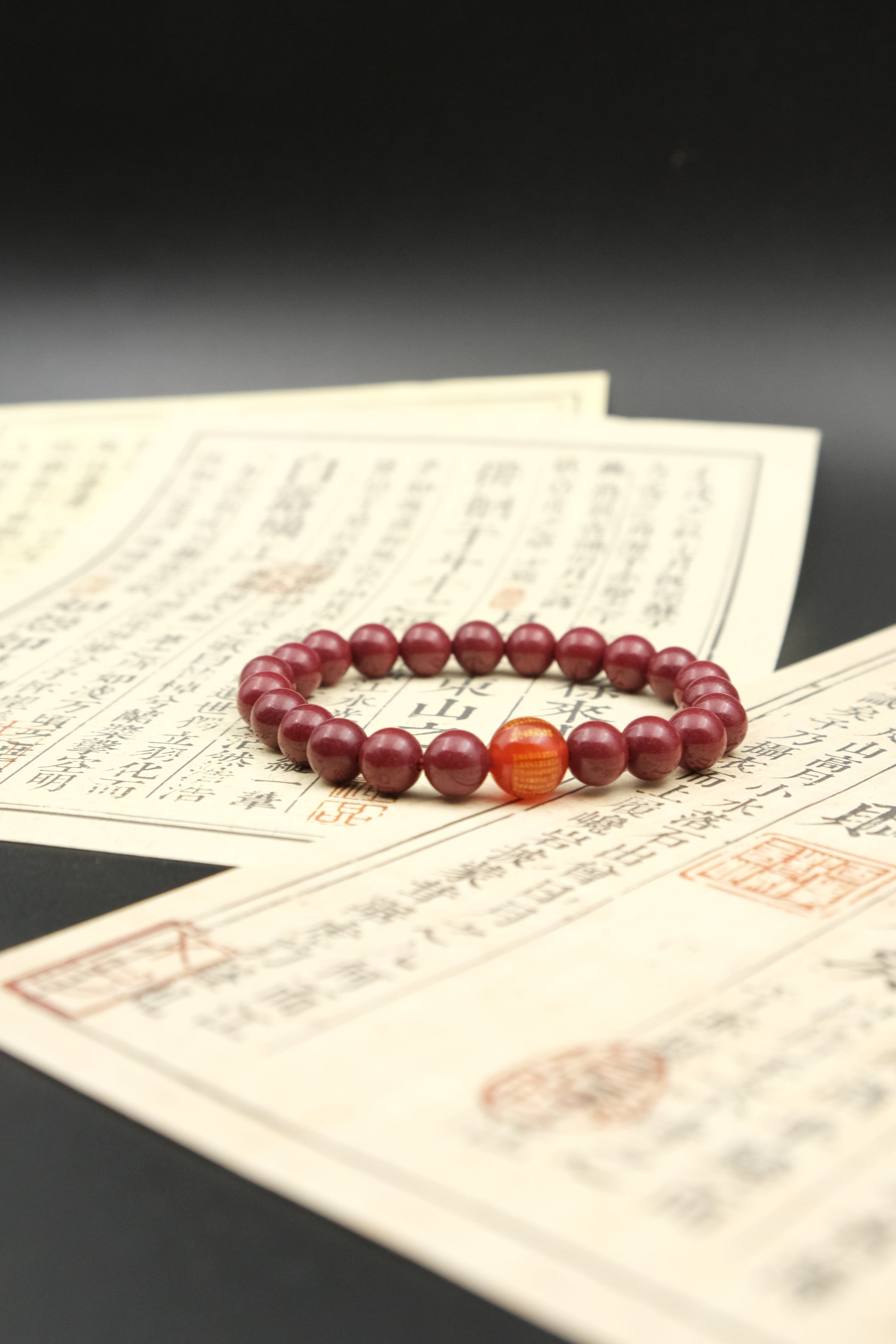 Red Cinnabar beaded bracelet, Emotional Balance, on top of an old document with a dark background