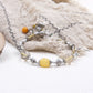 Tibetan Mantra Crystal Energy Beaded bracelet with yellow and orange beads on a textured fabric background