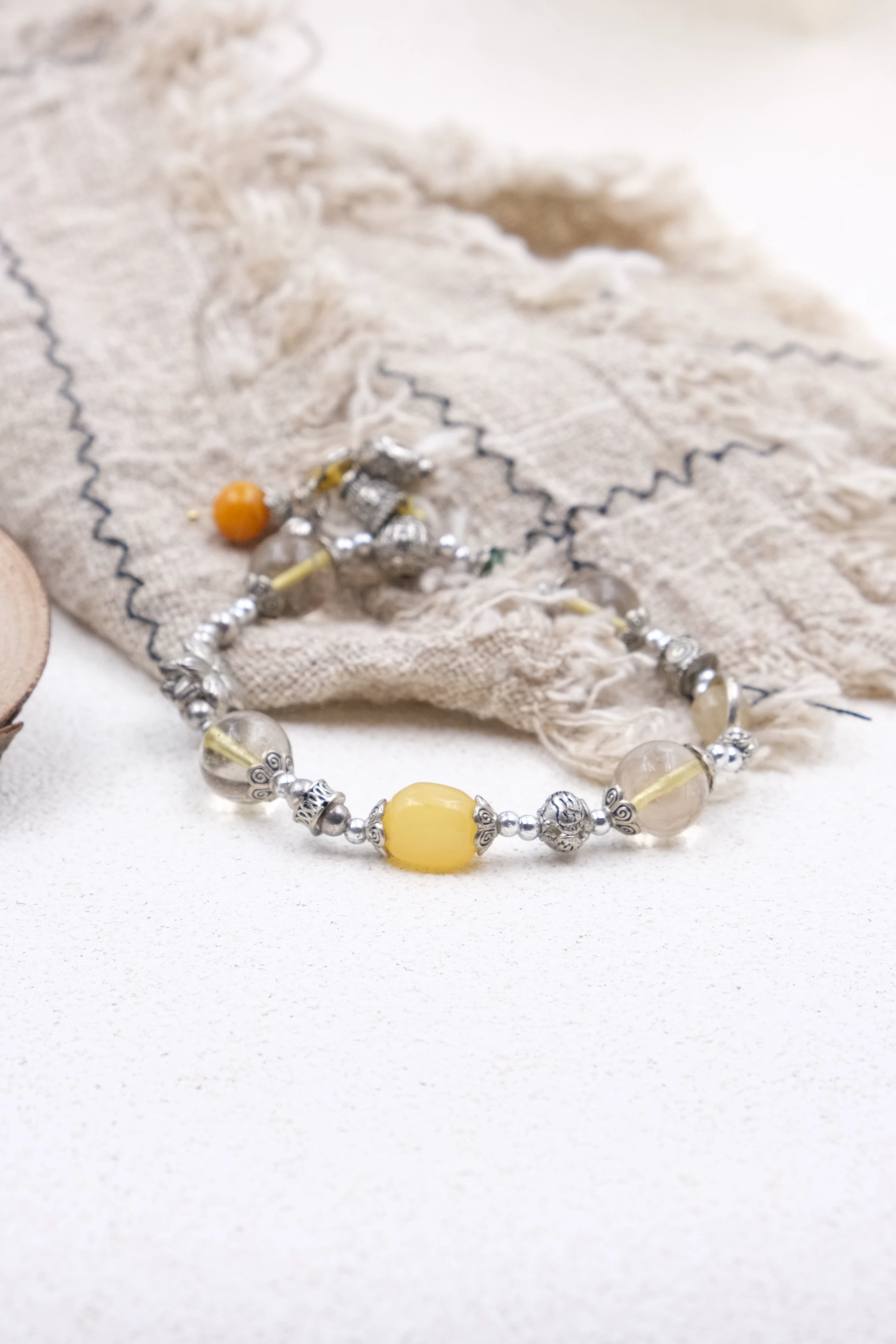 Tibetan Mantra Crystal Energy Beaded bracelet with yellow and orange beads on a textured fabric background
