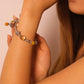 Close-up of a woman's arm wearing a Tibetan Mantra Crystal Energy beaded bracelet against a plain background
