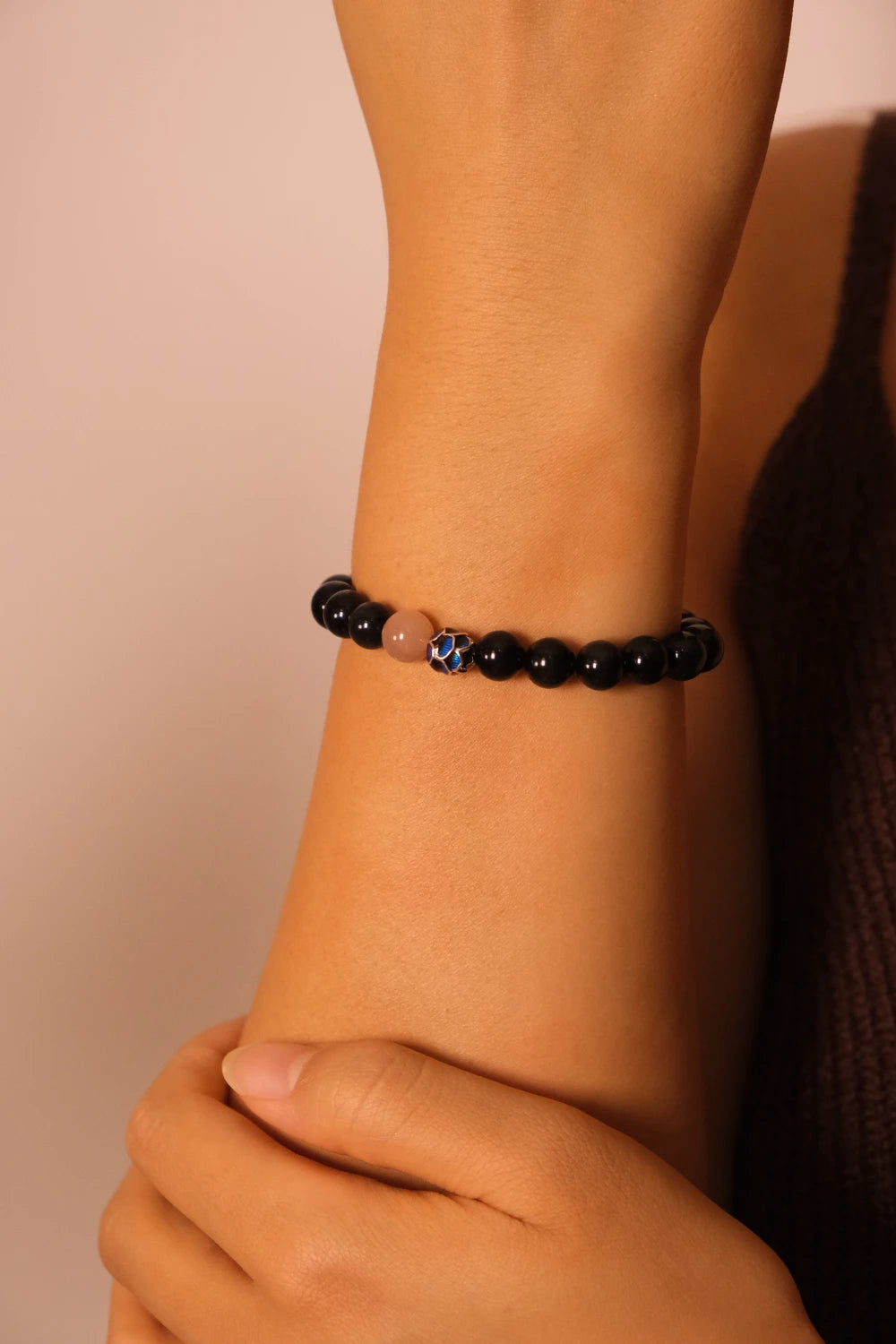 Close-up of a wrist wearing a Tibetan Meditation beaded bracelet against a neutral background