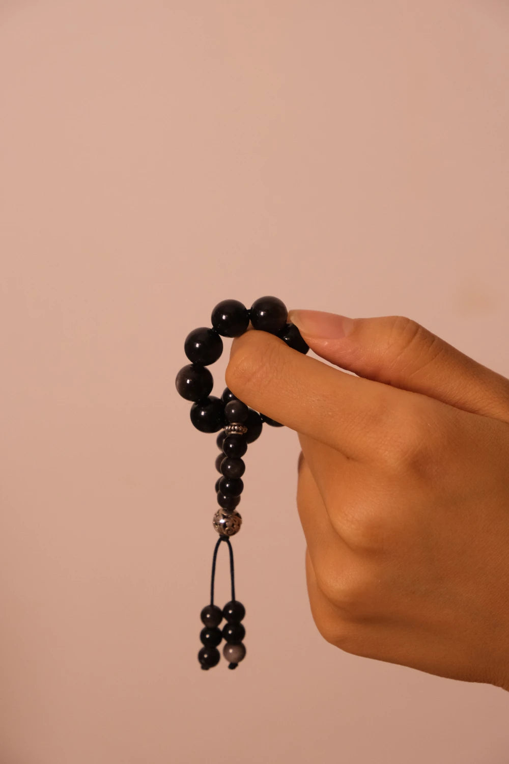 Hand holding Grounding & Protection – Tibetan Meditation Spinner against a beige background