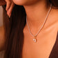 Close-up of a woman wearing a pearl necklace with a moon pendant.