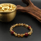 Tibetan Prosperity Energy Bracelet with amber and red beads next to a small brass container on a dark surface