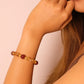 Close-up of a person wearing a Tibetan Prosperity Energy beaded bracelet on a plain background