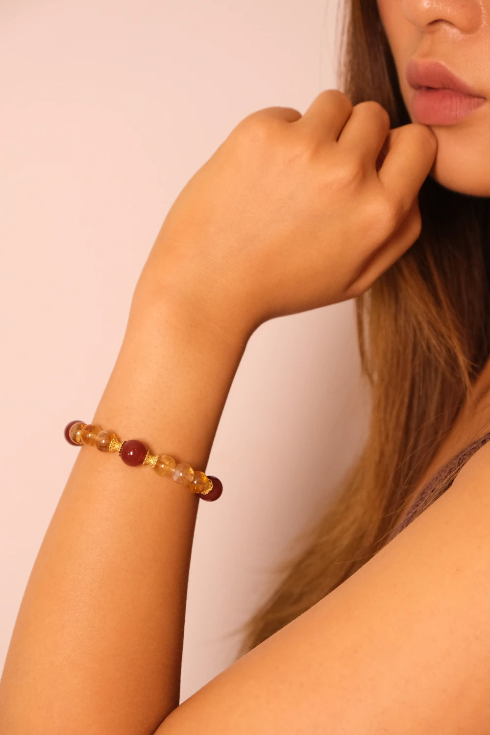 Close-up of a person wearing a Tibetan Prosperity Energy beaded bracelet on a plain background