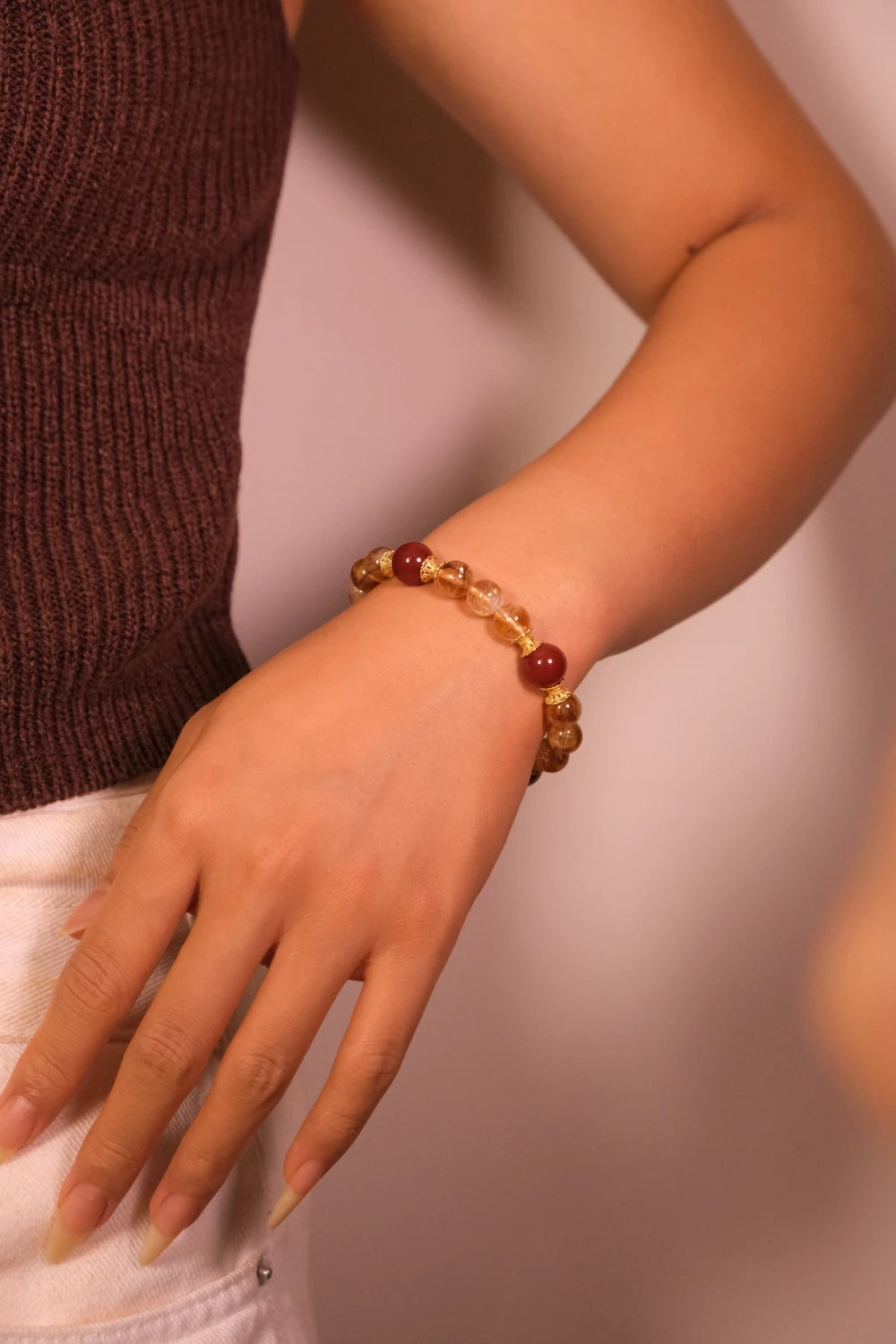 Hand wearing a Tibetan Prosperity Energy beaded bracelet on a blurred background