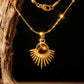 A gold necklace hanging on wood featuring a round brown Tiger's Eye stone set in a sunburst pendant.