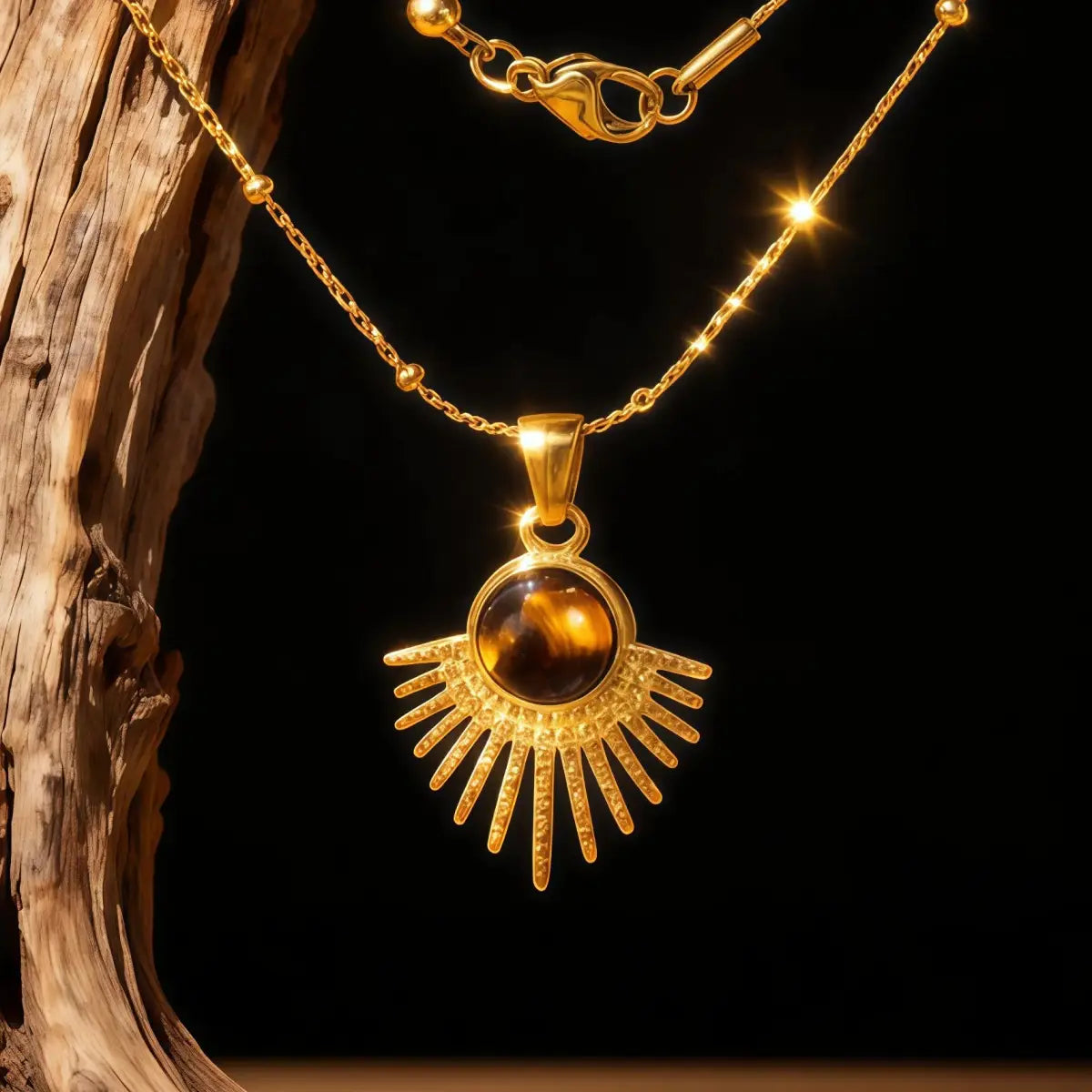 A gold necklace hanging on wood featuring a round brown Tiger's Eye stone set in a sunburst pendant.