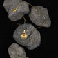 Tibetan Radiance Pendant Necklace with a sun design on tiger`s eye rocks against a black background