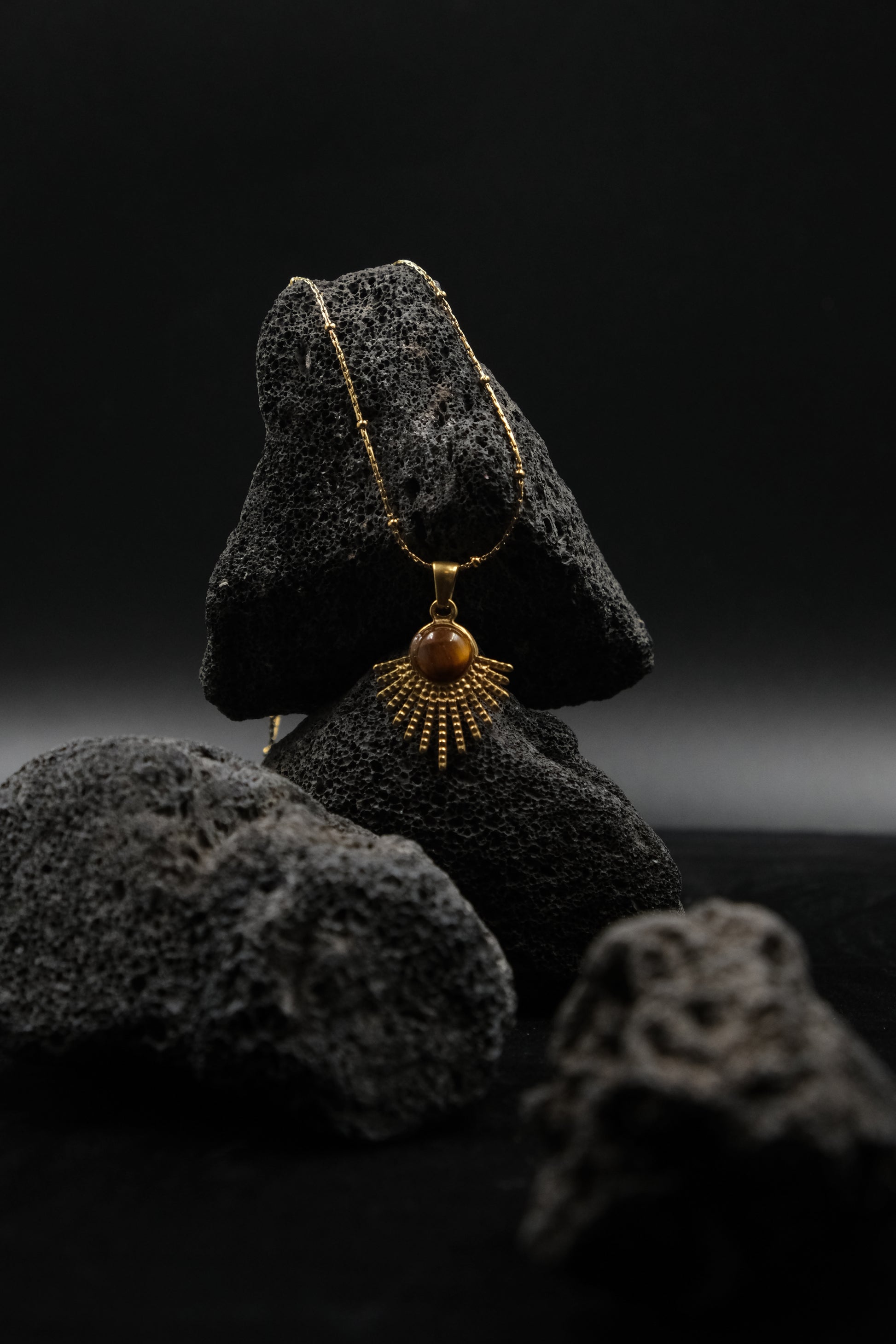 Gold necklace with a pendant on a  tiger`s eye stone against a dark background,  for Success & Abundance