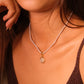 Close-up of a woman wearing a pearl necklace with a pendant.